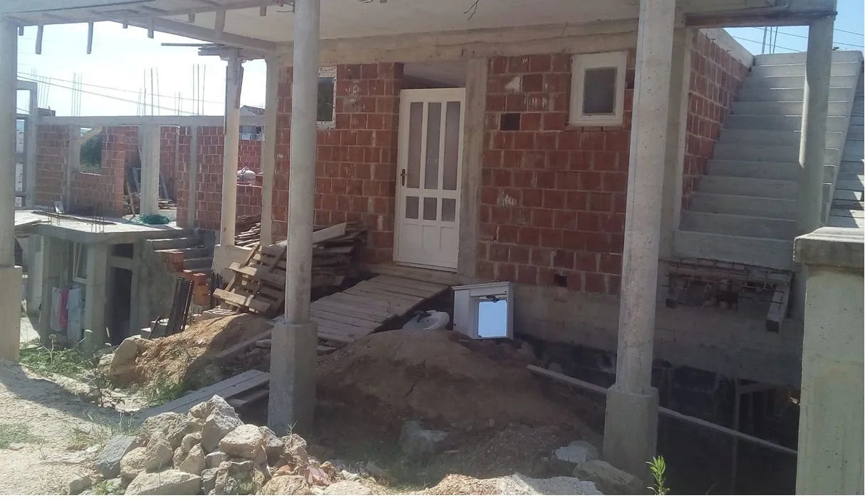 An unfinished house in the rough construction phase seen from the outside.