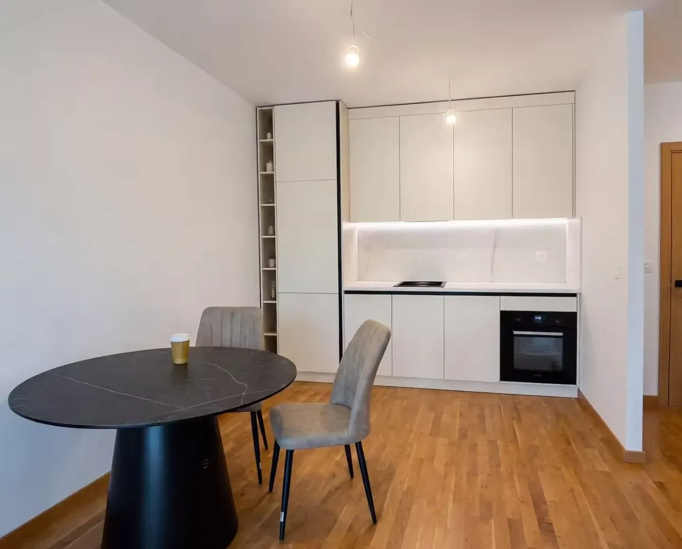 Modern kitchen with white cabinetry and a dining table with chairs.