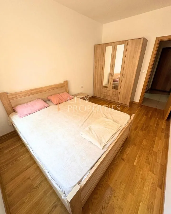 Namještena spavaća soba sa bračnim krevetom i drvenim ormarom.
