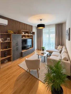 Living room with a sofa, TV, and wooden wall panel. - image 2