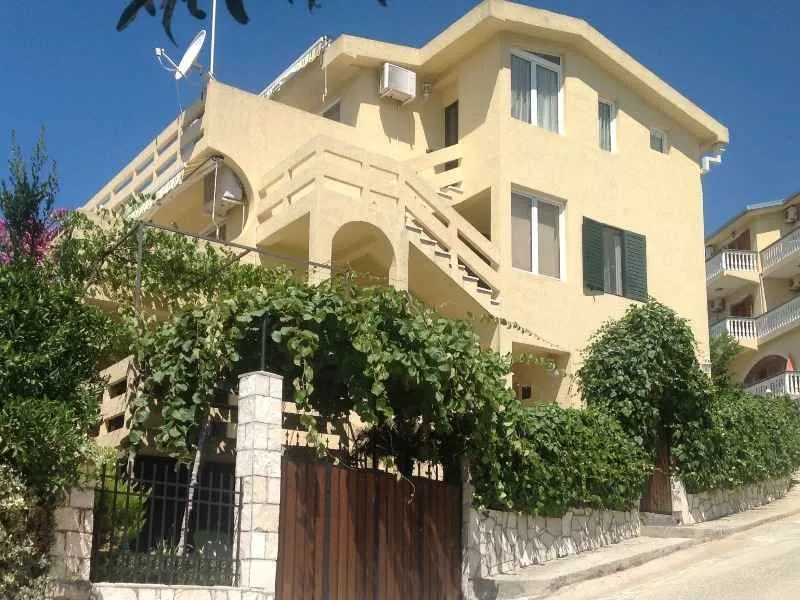 Pogled na spoljašnjost trospratne kuće sa dvorištem i terasama.