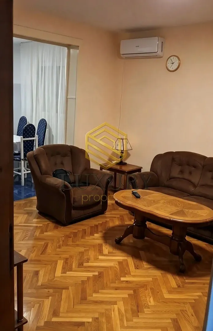 Dnevna soba sa garniturom, drvenim stolom i parketom.