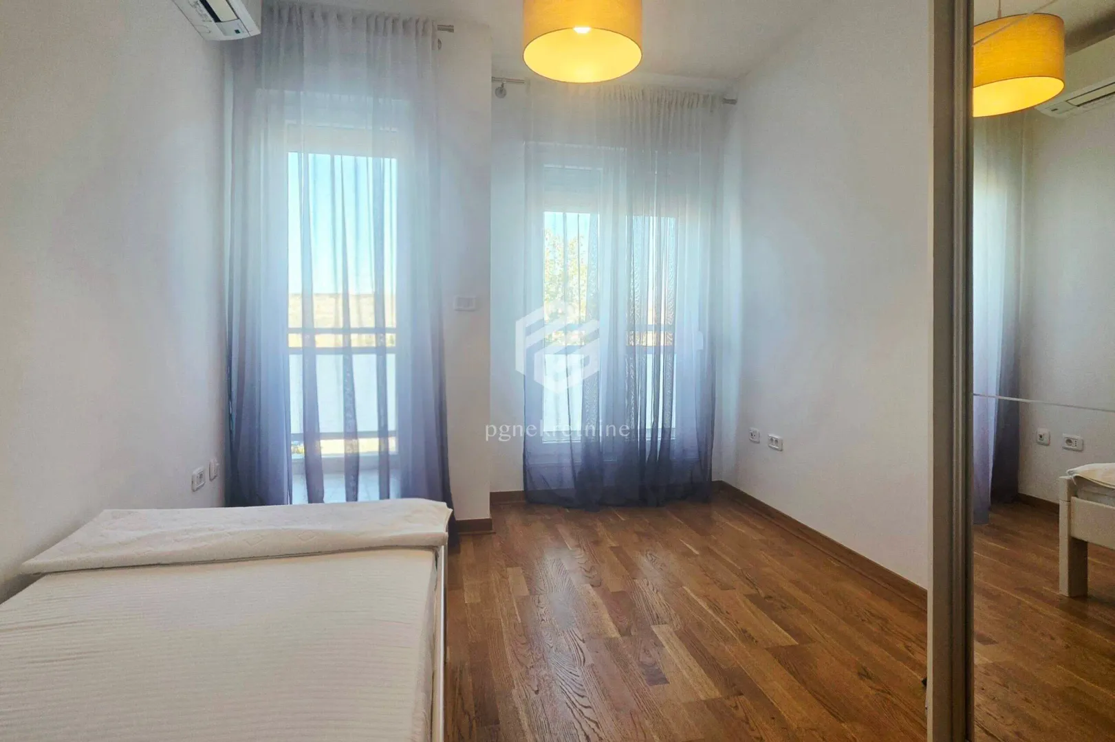 Bedroom with a bed, wooden flooring, and access to the terrace.