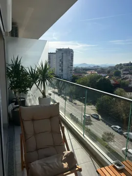 Namješten balkon sa staklenom ogradom i pogledom na gradsku ulicu. - image 2