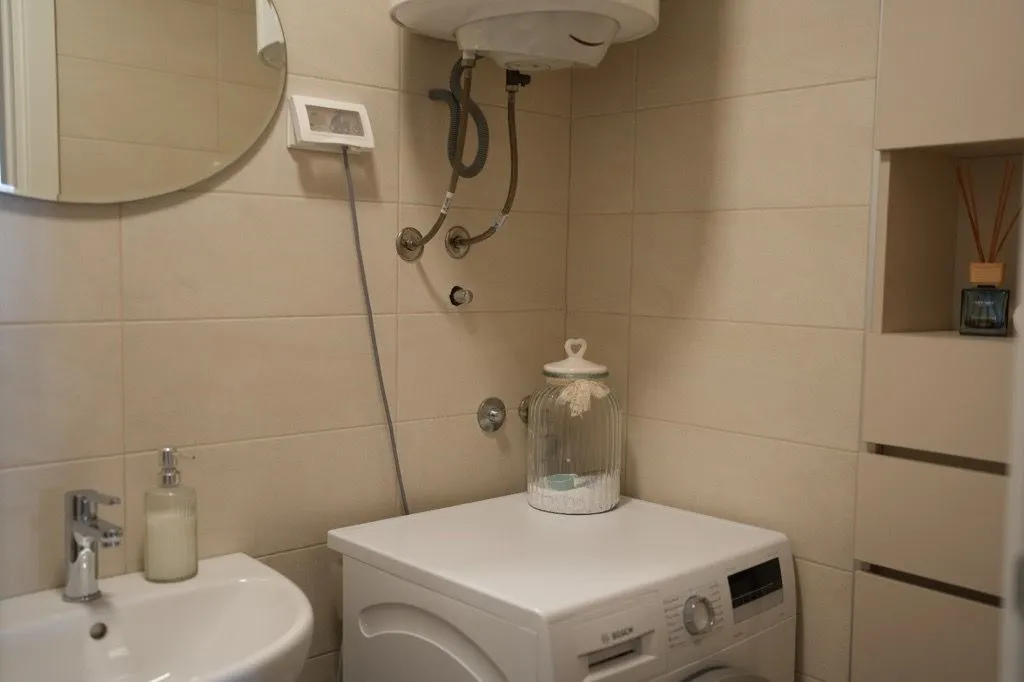 Bathroom with a washbasin, mirror and washing machine.