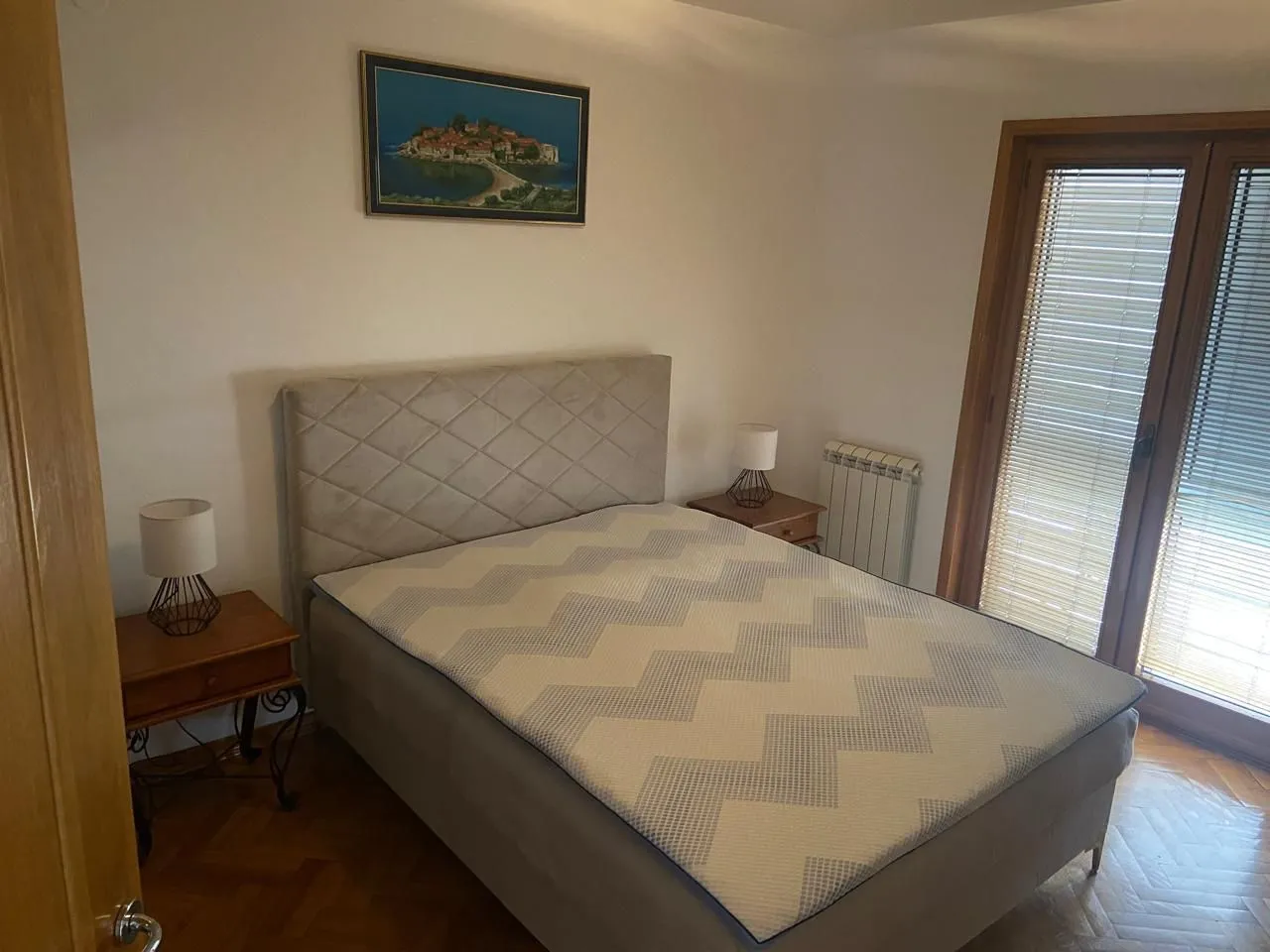 Bedroom with a double bed, bedside tables, and balcony doors.
