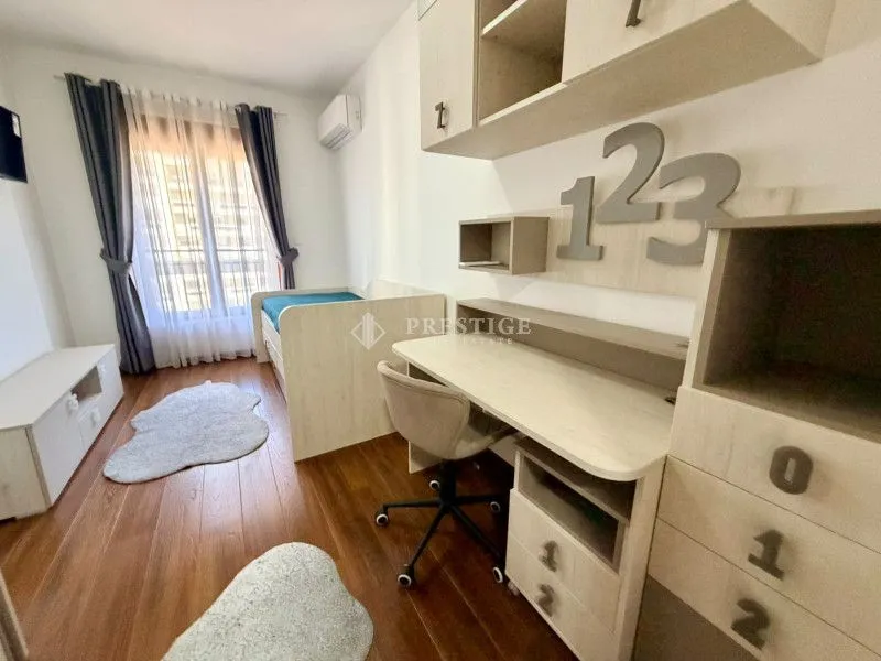 Dječija soba sa krevetom, radnim stolom i namještajem od svijetlog drveta.