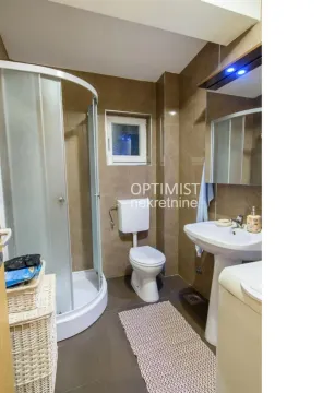 Bathroom equipped with a shower cabin, sink, toilet, and washing machine. - image 4