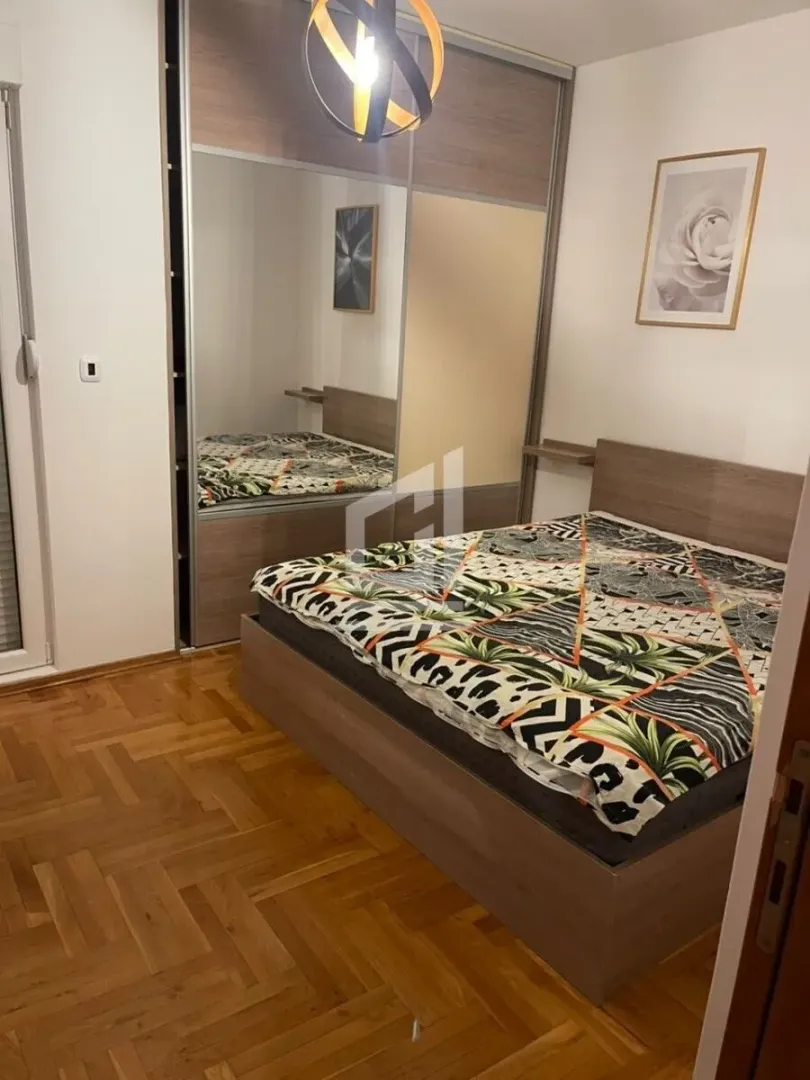 Furnished bedroom with a double bed, large wardrobe and parquet flooring.