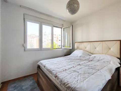 Spavaća soba sa bračnim krevetom i prozorom koji gleda na grad. - image 9