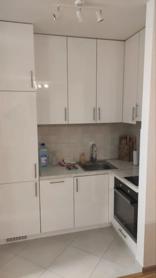 Small white kitchen with a sink, oven, and upper and lower cabinets.