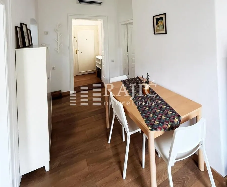 Dining area with a wooden table and white chairs in an apartment.