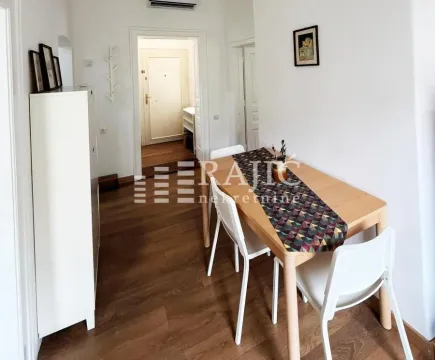 Dining area with a wooden table and white chairs in an apartment. - image 5
