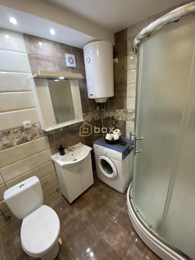 Bathroom equipped with a shower cabin, washbasin, washing machine, and water heater.