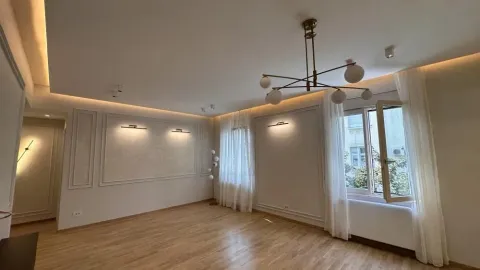 Spacious living room with wooden flooring, modern lighting, and wall moulding details. - image 2