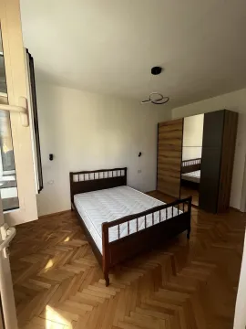 Svijetla spavaća soba sa drvenim krevetom, parketom i velikim ormarom. - image 11