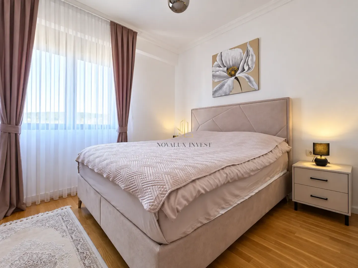 Furnished bedroom with a double bed, bedside table, and a window with curtains.
