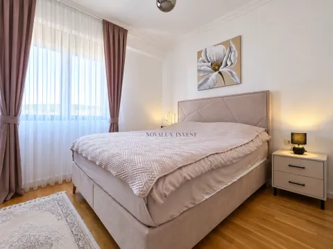 Furnished bedroom with a double bed, bedside table, and a window with curtains. - image 9