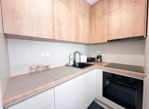 Small corner kitchen with wooden cabinets and built-in appliances. - image 7