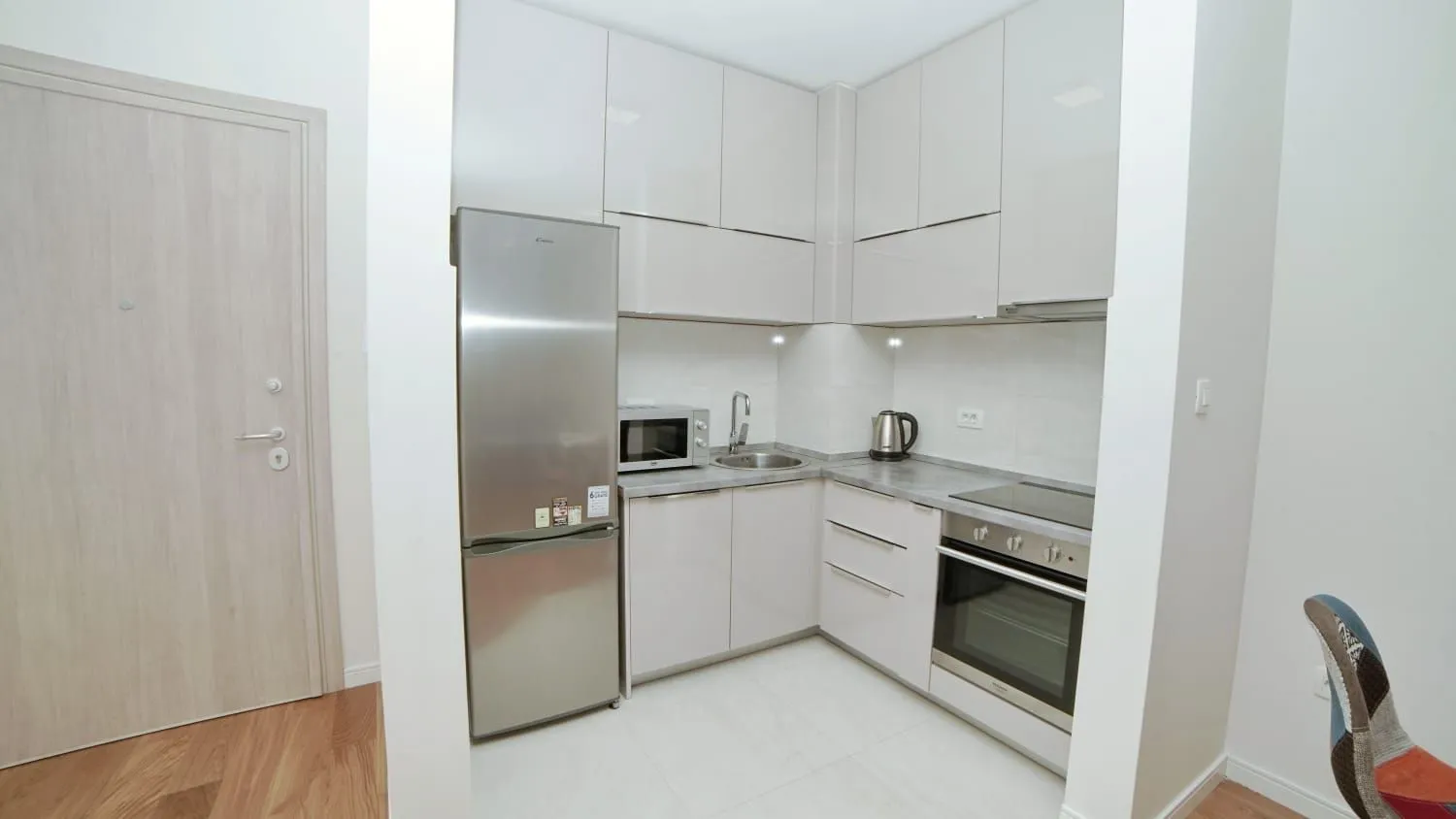 Small modern kitchen with light-colored cabinetry and built-in appliances.