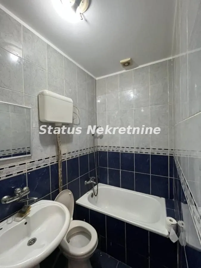 Manje kupatilo obloženo pločicama sa kadom, umivaonikom i WC šoljom.