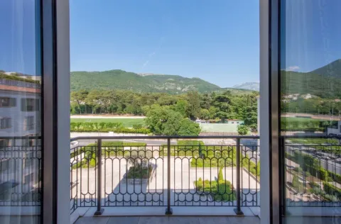 Pogled sa balkona na uređeno dvorište, zelenilo i planine u daljini. - image 14