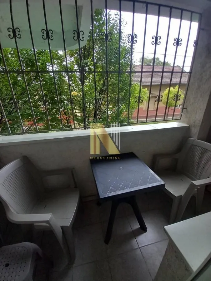 Manji balkon sa stolom i stolicama i zaštitnim rešetkama.