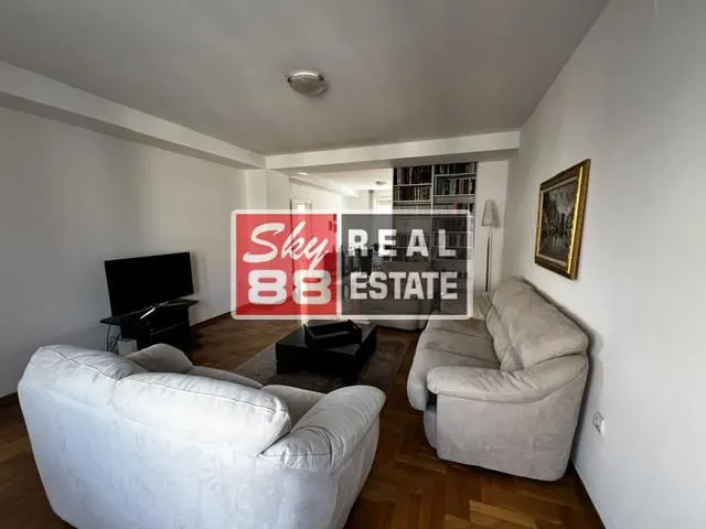 Dnevna soba sa garniturom za sedenje, televizorom i parketom.