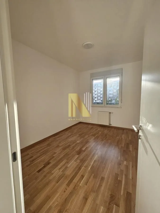Prazna soba sa parketom i prozorom.