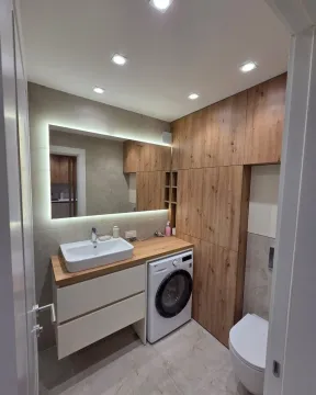 Modernly equipped bathroom with built-in units, washbasin, and washing machine. - image 10