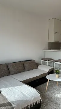 Svijetao dnevni boravak sa ugaonom garniturom, klub stolom i kuhinjskim šankom u pozadini. - image 3