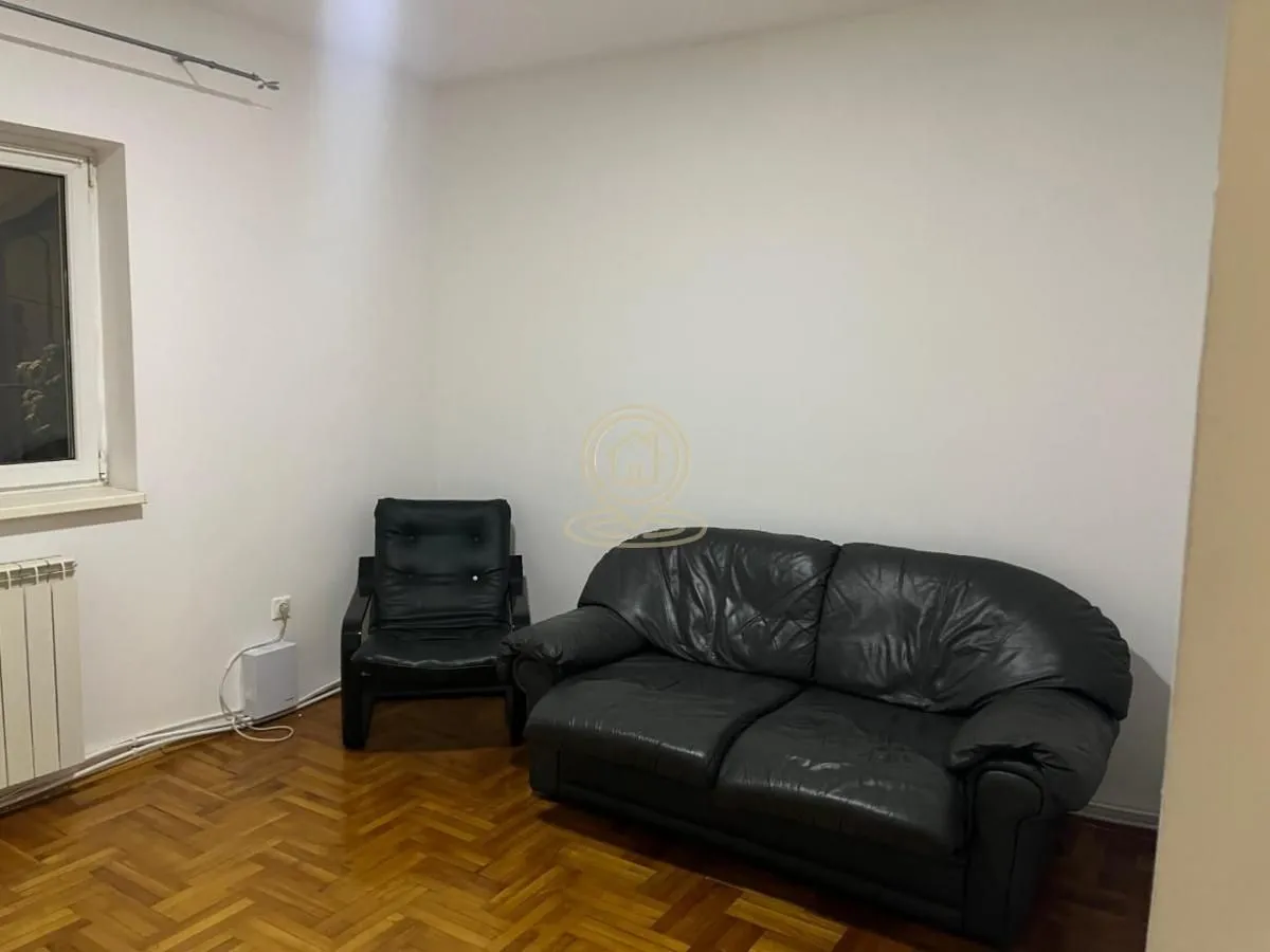 Living room with a black leather sofa set and hardwood parquet flooring.