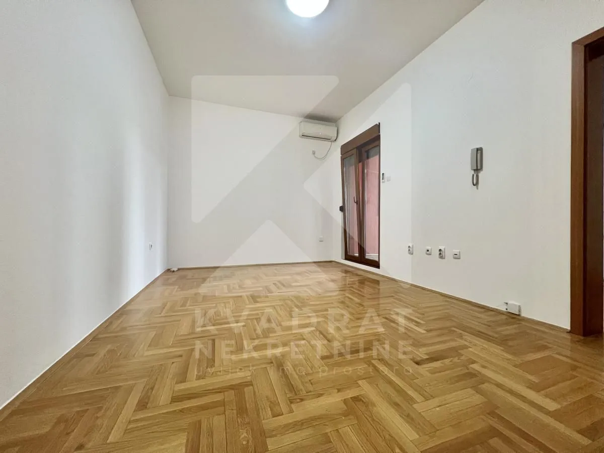 Empty room with parquet flooring, white walls, and a balcony door.