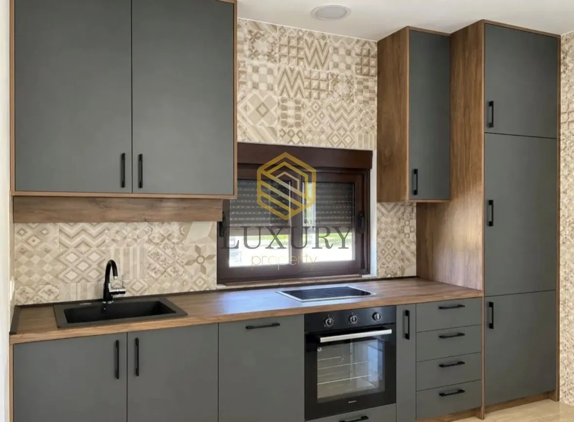 Modern kitchen with grey cabinets and a wooden countertop.
