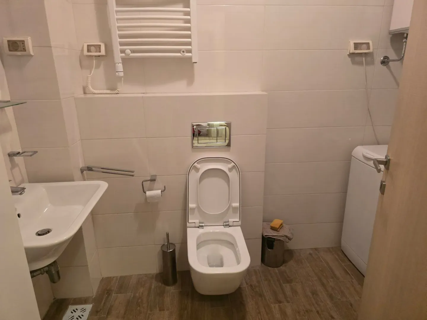 Uređeno kupatilo sa WC šoljom, umivaonikom i veš mašinom.