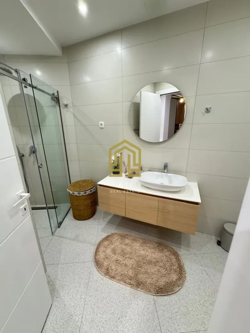 Moderne opremljeno kupatilo sa tuš kabinom i umivaonikom.