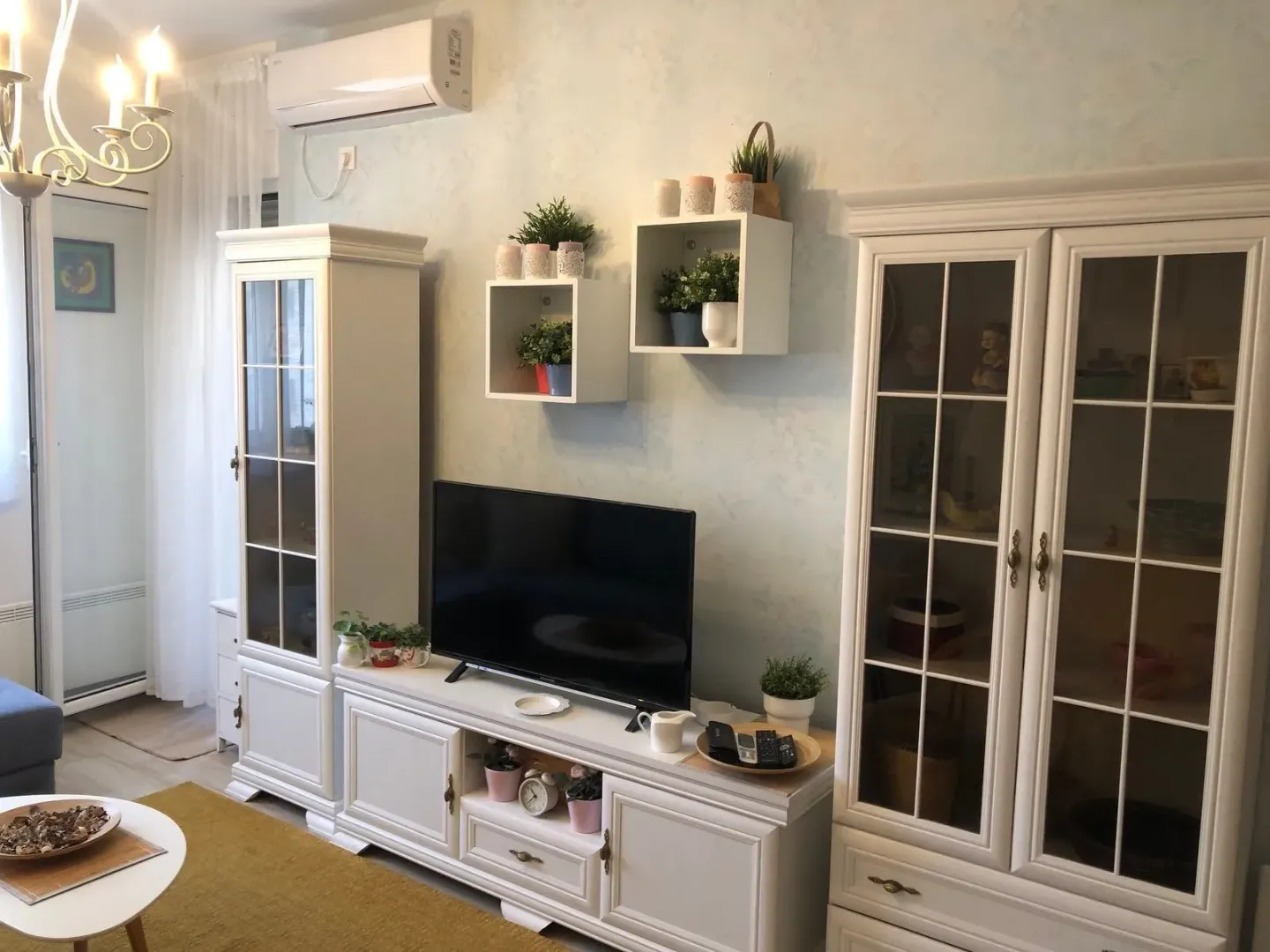 Living room with white furniture, television and decorative elements.