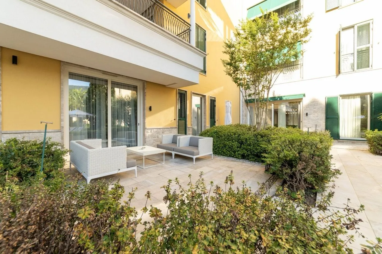 Popločana terasa sa garniturom za sjeđenje ispred stambene zgrade.