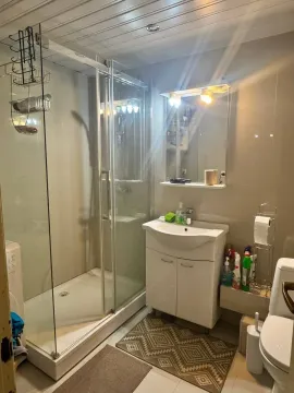 Small bathroom with a shower cabin, washbasin, and toilet. - image 10