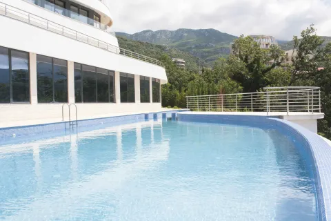 Spoljašnji bazen sa plavim mozaik pločicama ispred moderne zgrade. - image 3