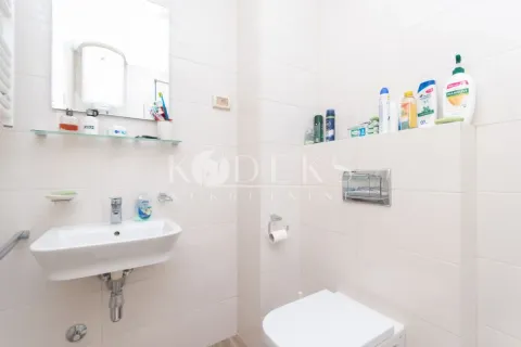 Bathroom equipped with a sink, toilet, and shelves with cosmetics. - image 9
