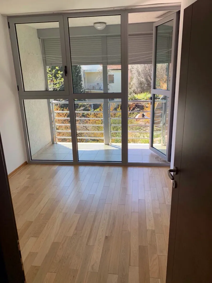 Prazna soba sa parketom i izlazom na balkon.