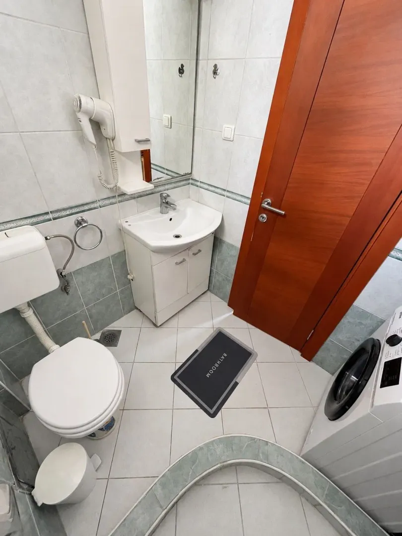 Small bathroom with a sink, toilet, shower cabin, and washing machine.