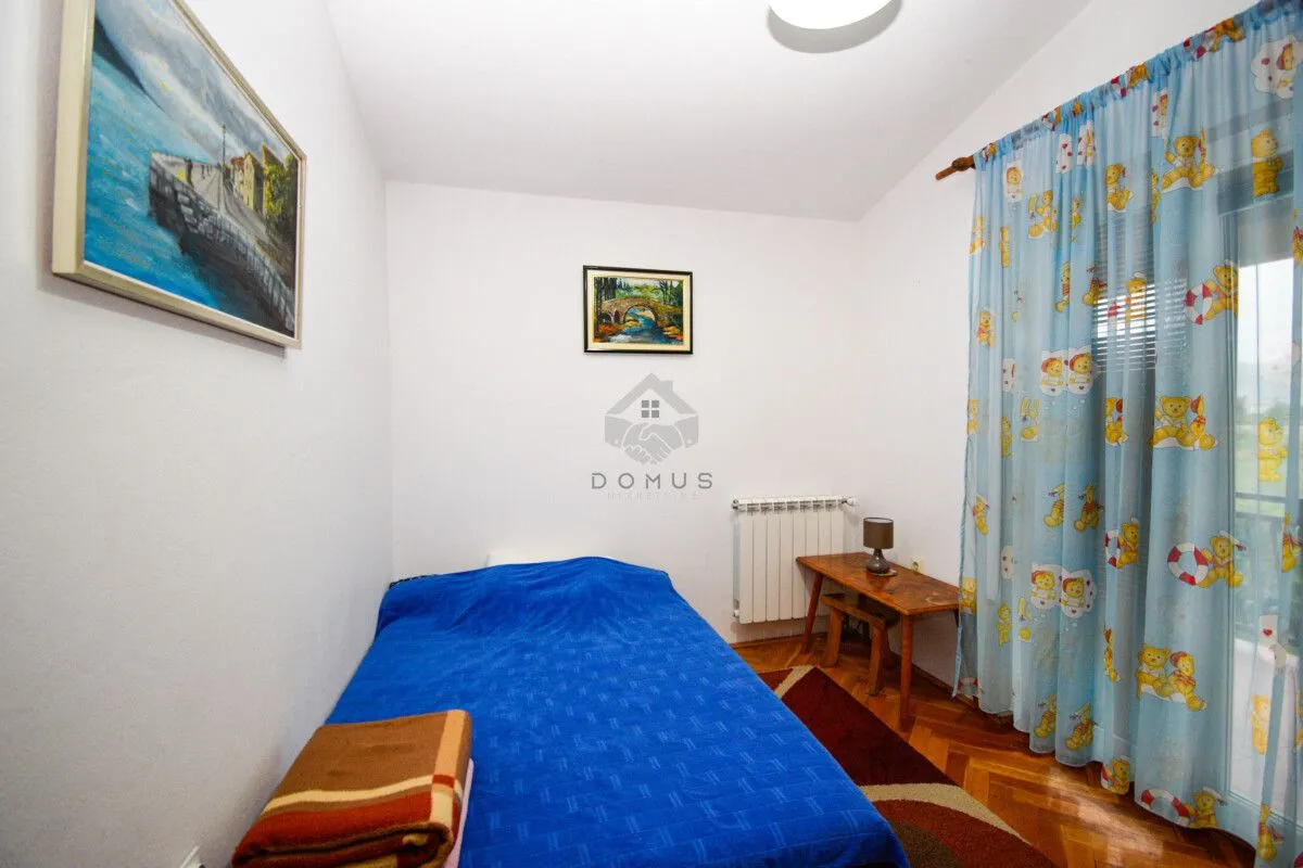 Smaller bedroom with a bed and blue curtains.