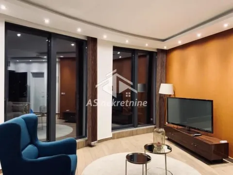 Dnevna soba sa TV komodom, foteljom i velikim staklenim površinama. - image 2