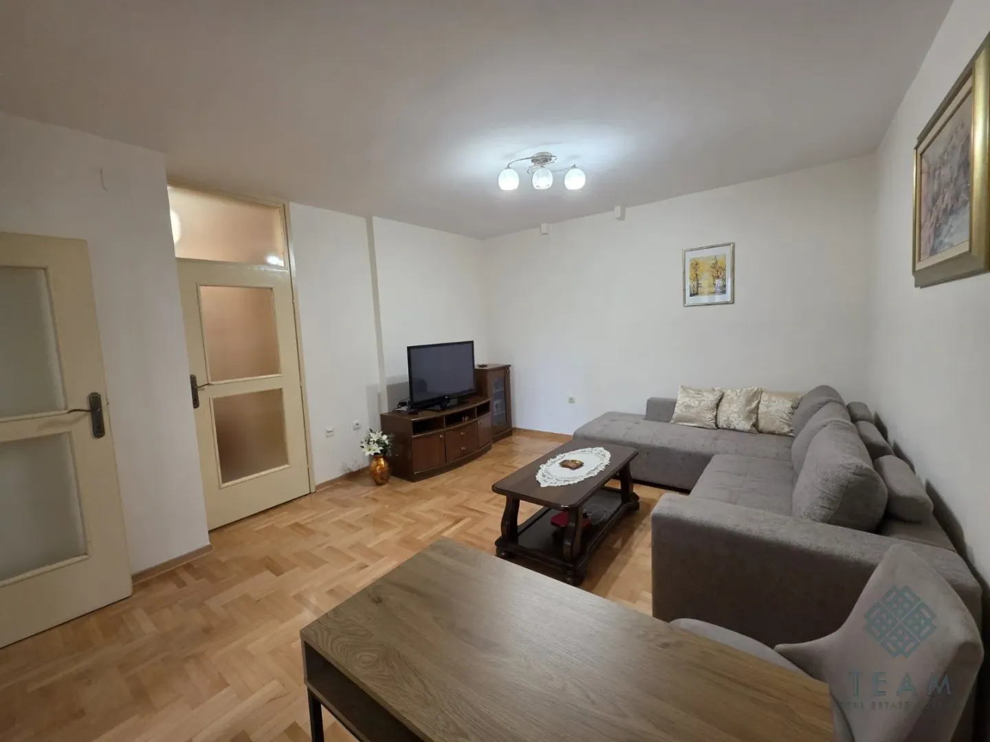 Living room furnished with a sectional sofa, television, and a wooden coffee table.
