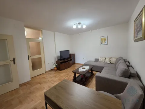 Living room furnished with a sectional sofa, television, and a wooden coffee table. - image 2