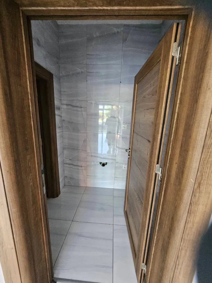 View of a bathroom tiled in grey with wooden doors.