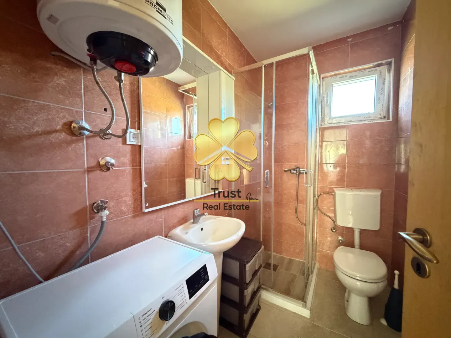 Tiled bathroom featuring a shower cabin, washbasin, and washing machine.