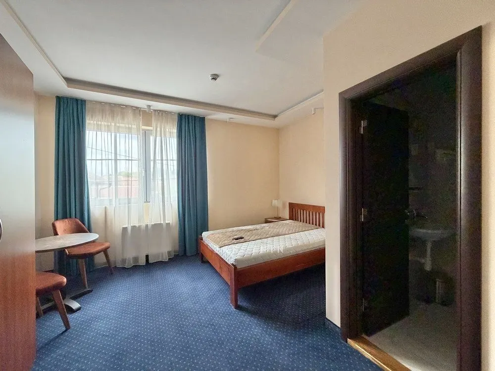 Furnished bedroom with a double bed, blue carpet, and an en-suite bathroom.